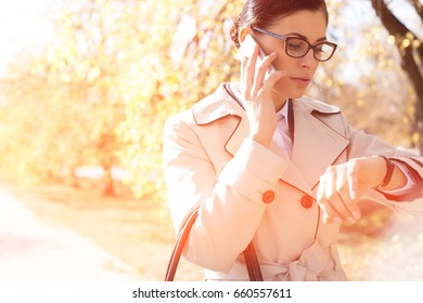 Businesswoman checking time while using cell phone at park - Powered by Shutterstock