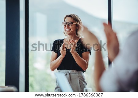 Businesswoman clapping hands after successful brainstorming session in boardroom. Business people women applauding after productive meeting.