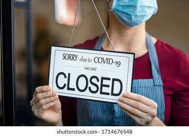 Businesswoman Closing Her Business Activity Due To Covid-19 Lockdown. Owner With Surgical Mask Close The Doors Of Her Store Due To Quarantine Coronavirus. Close Up Sign Due To The Effect Of COVID-19.