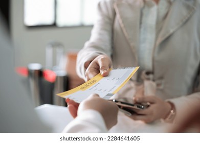 Businesswoman collecting her boarding pass from airlines ground attendant at airport departure gate or check in desk - Shutterstock ID 2284641605
