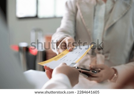 Businesswoman collecting her boarding pass from airlines ground attendant at airport departure gate or check in desk