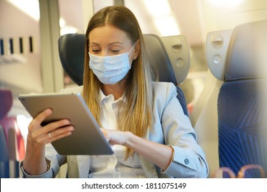 Businesswoman commuting by train, working on digital tablet and wearing face mask - Powered by Shutterstock