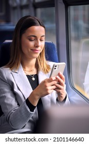 Businesswoman Commuting To Work On Train Looking At Mobile Phone