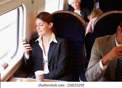 Businesswoman Commuting To Work On Train Using Mobile Phone