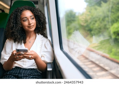 Businesswoman Commuting To Work On Train Sitting Checking Messages Or Social Media On Mobile Phone - Powered by Shutterstock