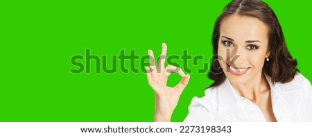 Businesswoman in confident cloth showing ok okay hand sign gesture, over blurred modern office background. Portrait of happy smiling gesturing business woman, green chroma key background