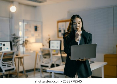 Businesswoman contemplates a work problem in an office at night. Exuding focus and determination as she navigates challenges. She appears confident and elegant. Embodying a successful entrepreneur - Powered by Shutterstock