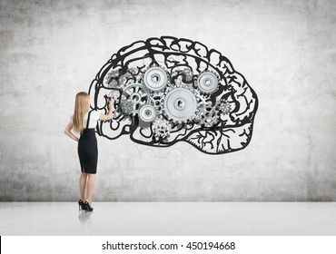 Geschäftsfrau zeichnet abstraktes Gehirn mit Metallgetrieben auf Betonwand im Raum. Brainstorming-Konzept