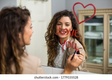 Businesswoman is drawing heart and  writing I love you with lipstick on the mirror while preparing for work. - Powered by Shutterstock