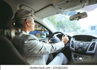 Businesswoman Driving A Car. Shot From Behind Of Senior Female In Businesswear Driving A Car.