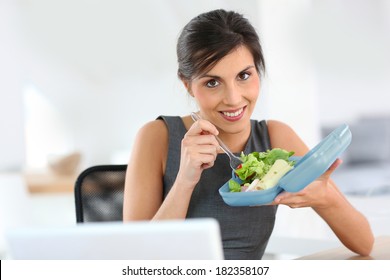 Businesswoman Eating From Lunch Box In Office