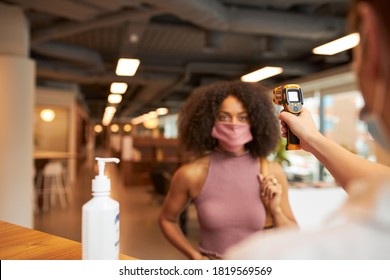 Businesswoman Entering Office Having Temperature Checked With Digital Thermometer During Pandemic - Powered by Shutterstock