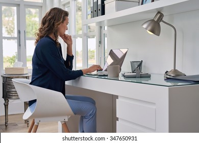 Unternehmerin, die auf Laptop aus dem Heimbüro arbeitet