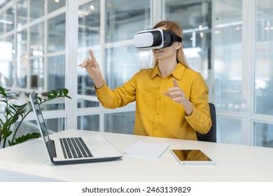 Businesswoman exploring virtual reality with VR headset while sitting at her desk in a contemporary office space. - Powered by Shutterstock