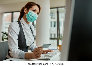 Businesswoman with face mask using computer and shopping on the internet with credit card in the office during COVID-19 pandemic.  - Powered by Shutterstock