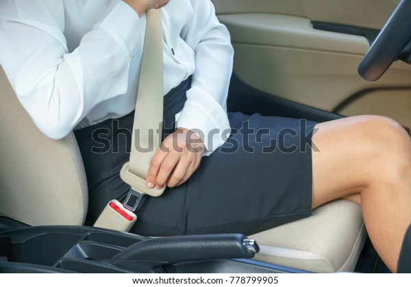 Businesswoman\
fastening seat belt in car before\
driving