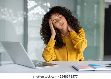 Businesswoman feeling stressed with headache at desk using laptop. Concept of stress, burnout, and work pressure in office setting and modern business environment. - Powered by Shutterstock