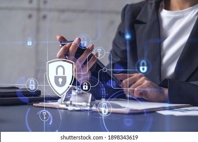 A businesswoman in formal wear checking the phone to sign the contract to prevent probability of risks in cyber security. Padlock Hologram icons over the working desk. - Shutterstock ID 1898343619