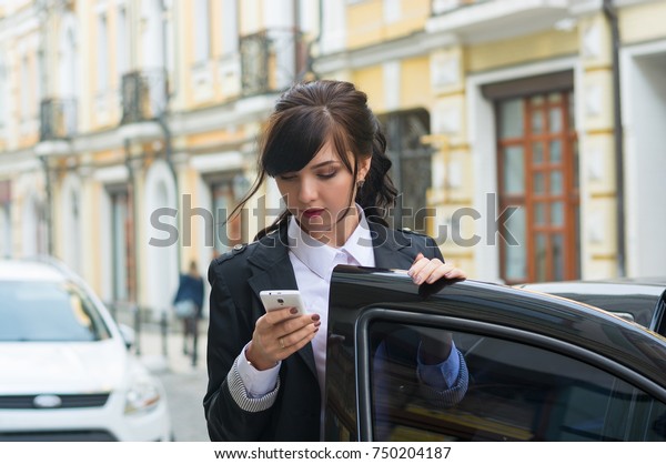 Business-woman gets into the car and talks on\
mobile phone