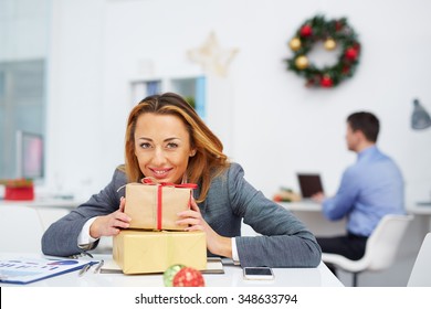 Businesswoman With Gifts Looking At Camera In Office On Christmas Day