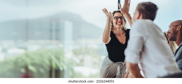 Businesswoman giving high five to male colleague in meeting  Business professionals high five during meeting in boardroom 