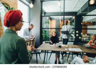 Businesswoman Giving A Speech During An Office Meeting. Muslim Businesswoman Sharing Her Creative Strategy With Her Colleagues. Female Team Leader Wearing A Headscarf In A Multicultural Workplace.