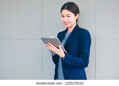 A Businesswoman In A Grey Dress And Navy Blue Suit Hold Ipad