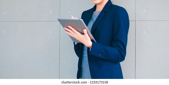 A Businesswoman In A Grey Dress And Navy Blue Suit Hold Ipad