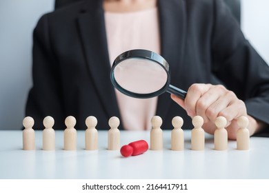 Businesswoman hand holding magnifying glass for recruiting leader man wooden from crowd of employees.Human resource management, Recruitment, Teamwork, hiring and leadership Concepts