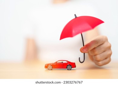 Businesswoman hand holding red umbrella and cover red car toy on table. Car insurance, warranty, repair, Financial, banking and money concept - Powered by Shutterstock