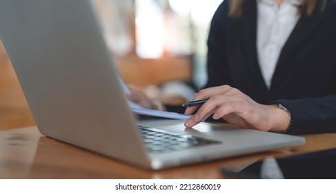 Businesswoman hand is on laptop trackpad, working on paperwork or business document at office, a corporate businesswoman, accountant working.