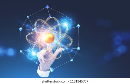 Businesswoman hand touching glowing gold and blue atom model over blurred dark blue background. Concept of science, chemistry and physics. Copy space toned image double exposure