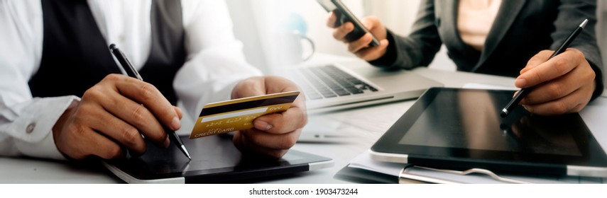 businesswoman hand using smart phone, tablet payments and holding credit card online shopping, omni channel, digital tablet docking keyboard computer at office in sun light - Shutterstock ID 1903473244