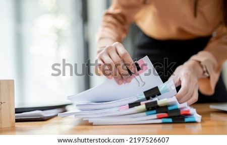 Businesswoman hands working in Stacks of paper files for searching and checking unfinished document achieves on folders papers at busy work desk office