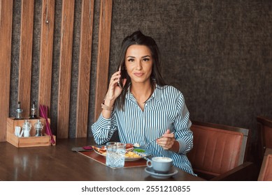 Businesswoman is having a healthy lunch and talking on the phone while sitting in a modern restaurant - Powered by Shutterstock