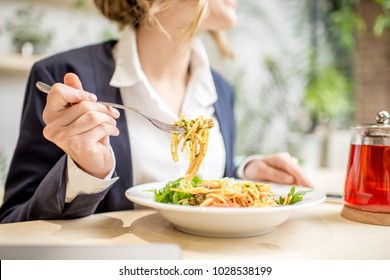 Businesswoman having lunch with pasta and fruit tea at the vegan restaurant on the green background