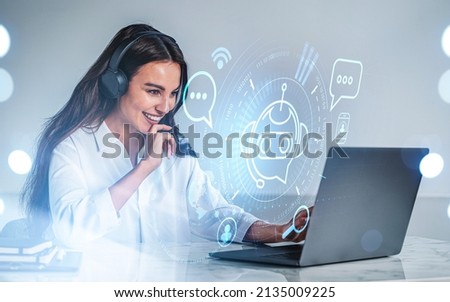 Businesswoman in headphones laugh, typing on laptop, hologram of voice chat. Hud with bot icon and social network. Office table with computer. Concept of video call and artificial intelligence