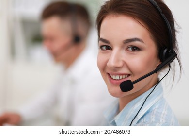 Businesswoman with headset smiling at camera in call center