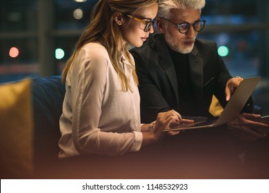 Businesswoman with her boss sitting in office and working on laptop. Two business people working late in office with finish a project. - Powered by Shutterstock