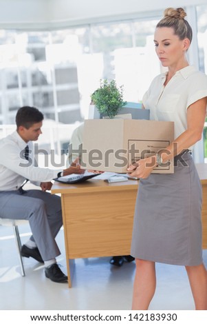 Businesswoman holding a box and her colleagues in the bottom in the office