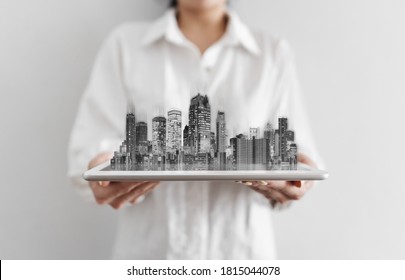 Businesswoman Holding Digital Tablet, And Modern Buildings Hologram. Real Estate Business And Building Technology 