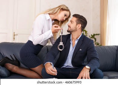 Businesswoman Holding Handcuffs For Businessman In Office