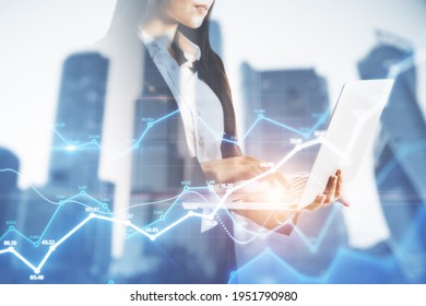 Businesswoman holding a laptop and watching on the holo tading charts, background with city view, market and analysis concept, double exposure - Powered by Shutterstock