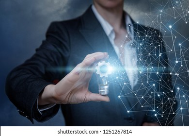A businesswoman is holding a lightbulb with a cogwheel mechanism inside with wireless connections by its side. The concept is the functional thinking principle. - Shutterstock ID 1251267814