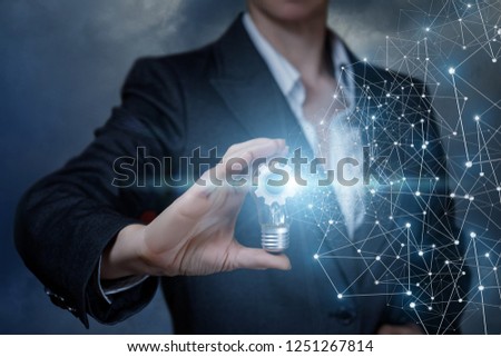 A businesswoman is holding a lightbulb with a cogwheel mechanism inside with wireless connections by its side. The concept is the functional thinking principle.