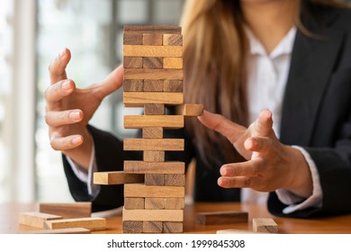 businesswoman holds her hand on a wooden block with a weak base. It is like a business risk mitigation strategy. and project management the best of the business