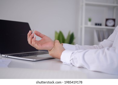 Businesswoman hurts wrist while working. A woman uses a computer for a long time causing Trigger Finger. Office Syndrome Concept.
