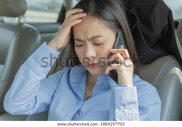 Businesswoman inside a car using a mobile phone\
for working and she is\
Headache.