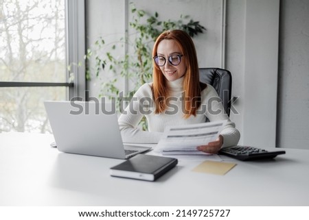 Businesswoman with invoices and documents calculating rates and KPIs. Cheerful business lady in an office working. Manager employee, account manager, accountant