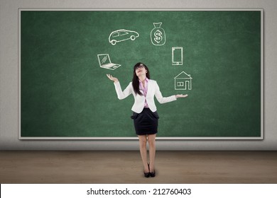 Businesswoman juggling responsibilities over blackboard in the classroom